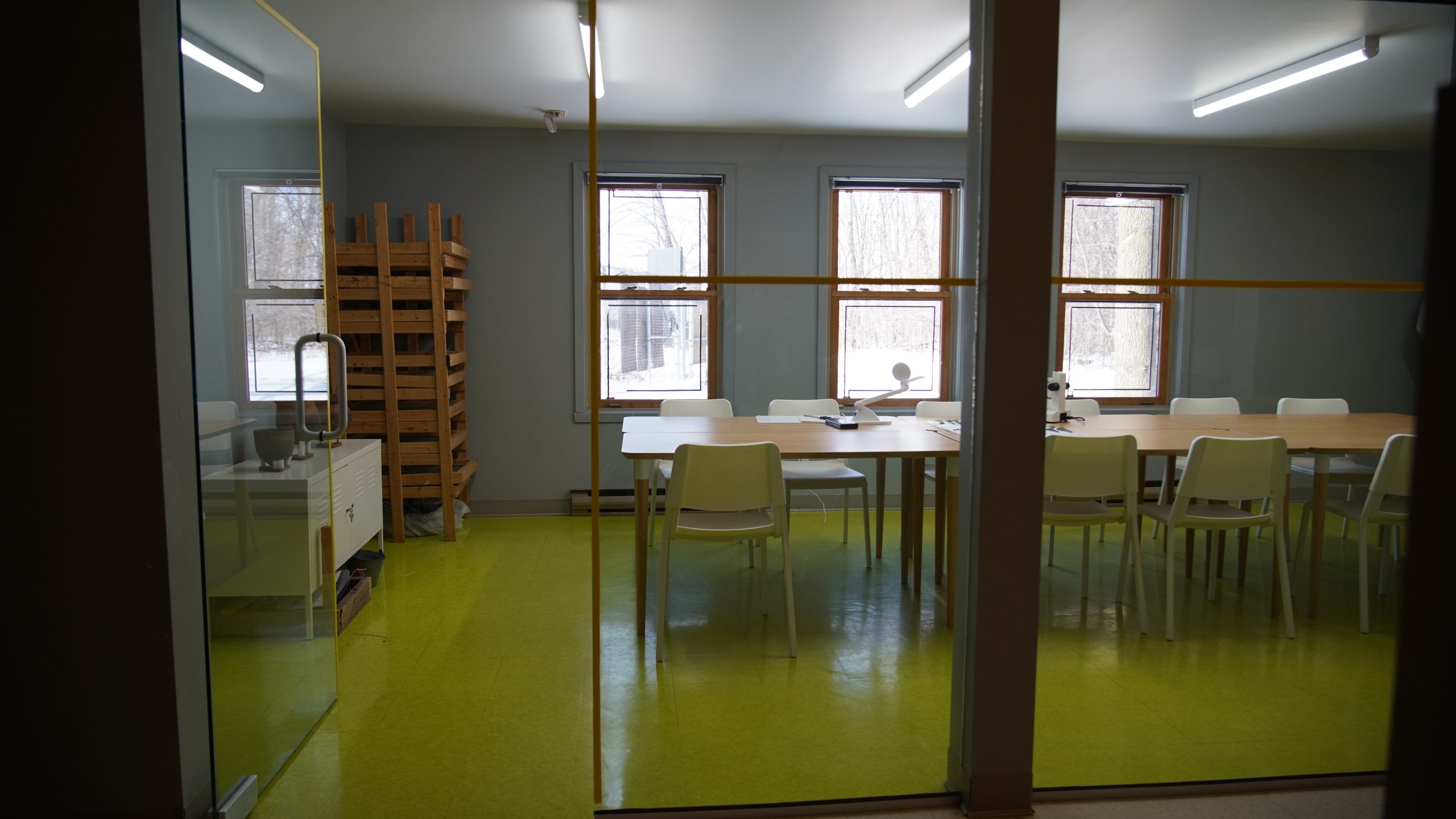 Salle avec une grande table en bois et plusieurs chaises blanches située dans le laboratoire